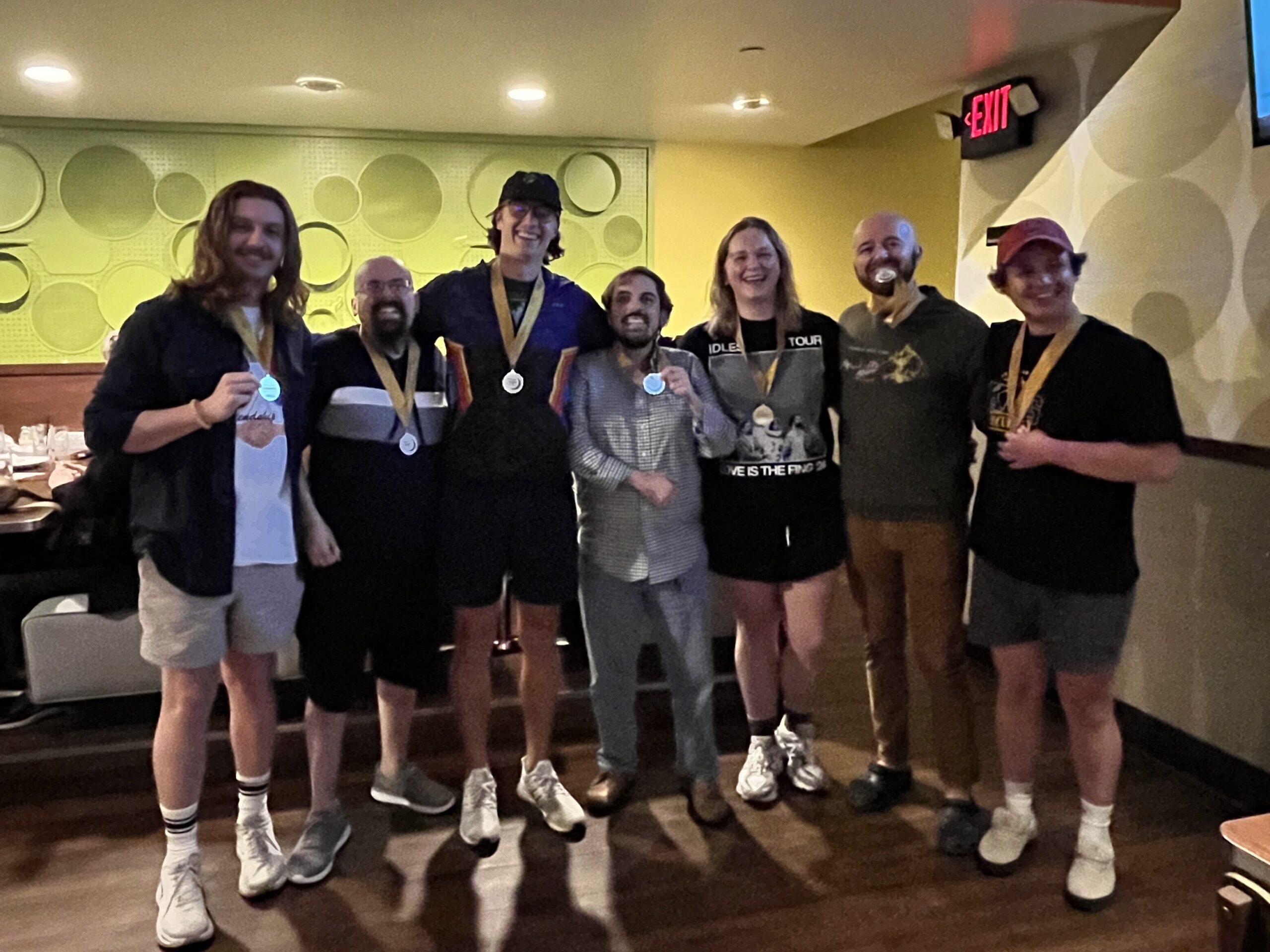 A group of people wearing medals in a bar. They won pub trivia championship.